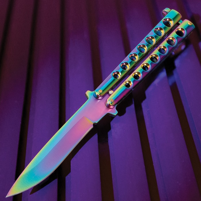The Rainbow Butterfly Knife has a skeletonized steel handle and 4” stainless steel blade, both with rainbow finish.