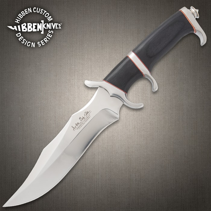 Legacy III fighter knife with black, silver, and red accents on a background of black rocks.