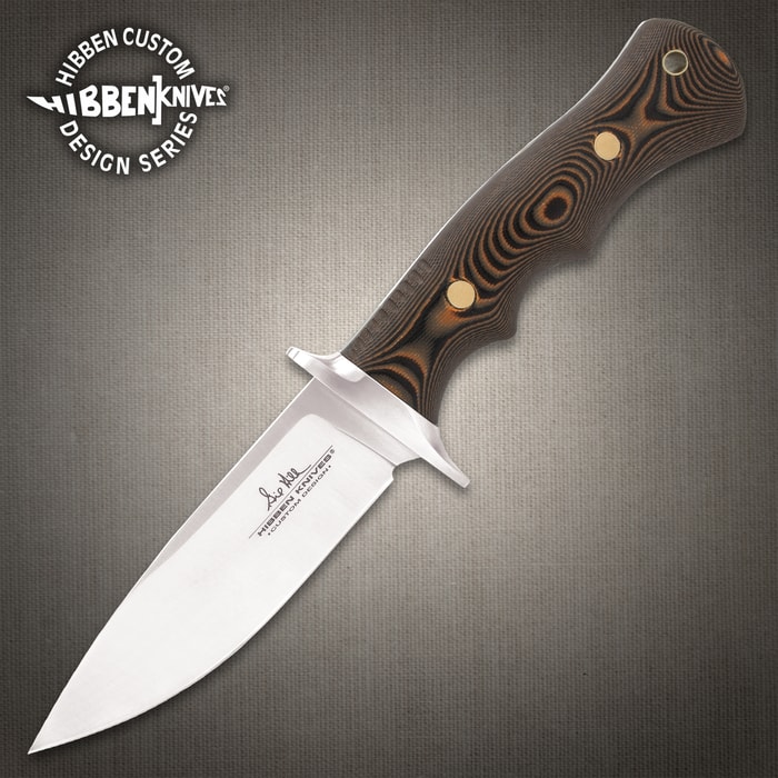 9 5/8" stainless steel fixed blade knife with G10 curved handle and brass pins on a background of moss, greenery, wood, and seude.