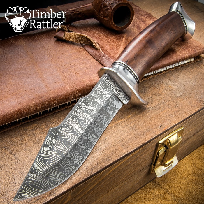 Knife with patterned blade and wooden handle on leather surface