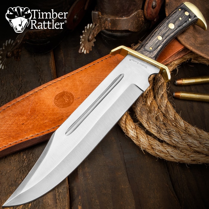 Large bowie knife with wooden handle and leather sheath on wooden surface